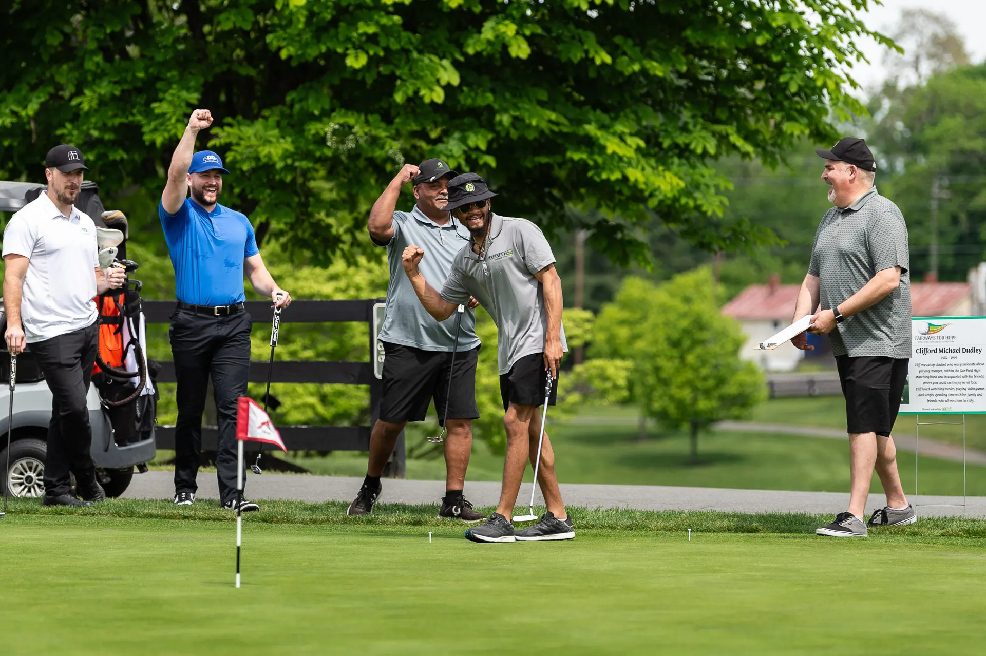 Golfers cheering a putt on the green at the Fairways for Hope tournament