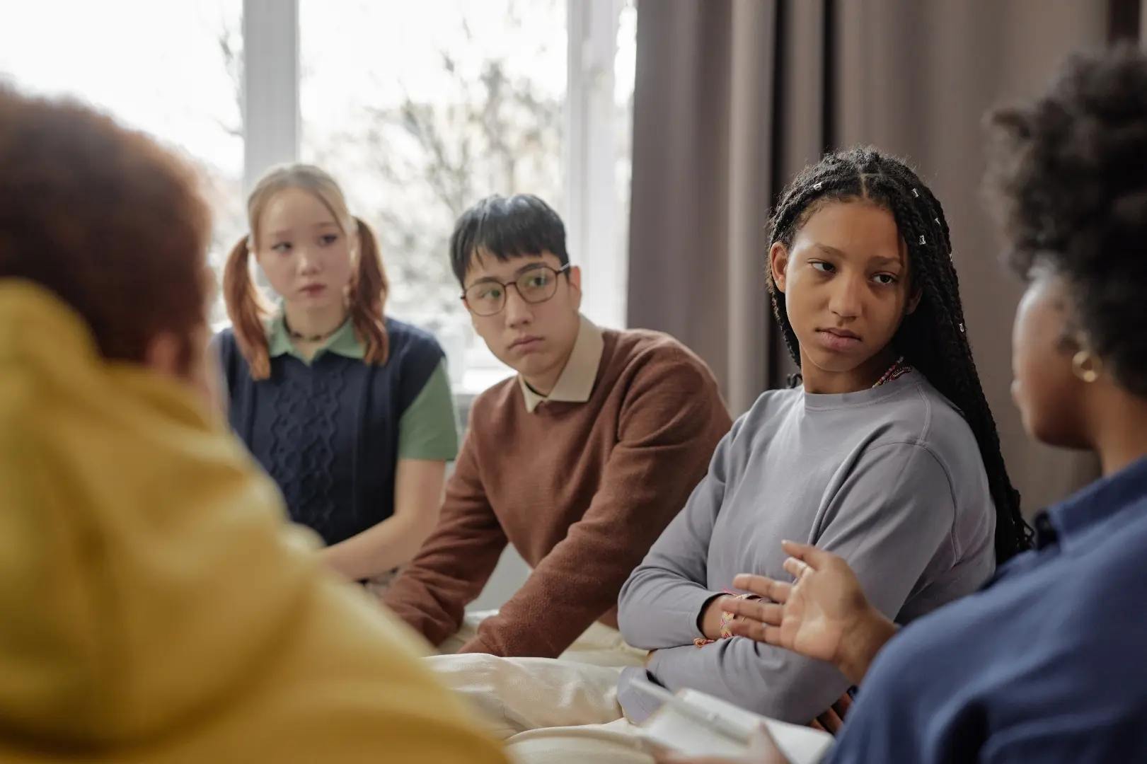 A caring mental health professional meeting one-on-one with a teenager in a warm, supportive setting
