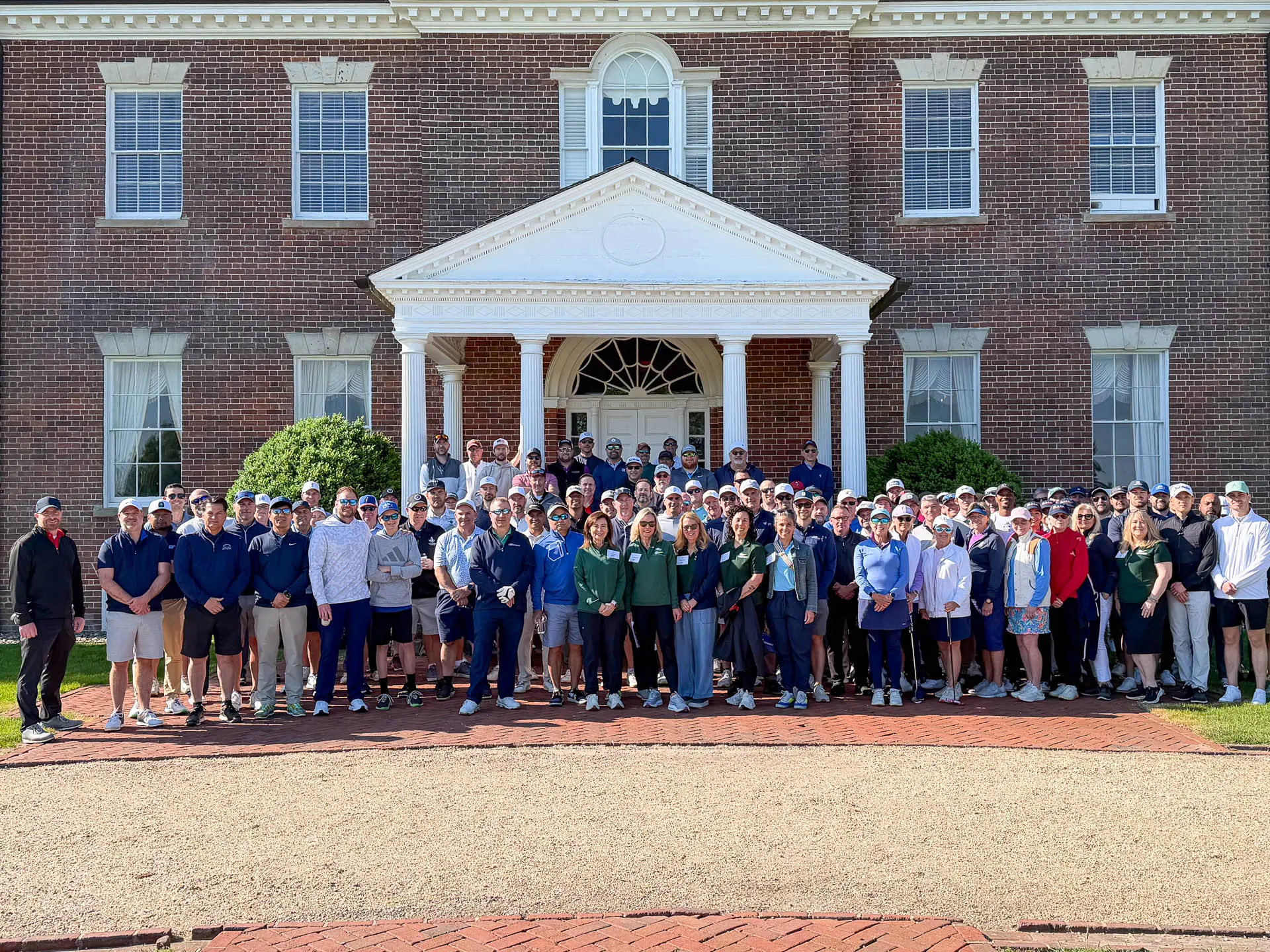 Tournament participants gathered for a group photo in front of the Belmont Country Club clubhouse