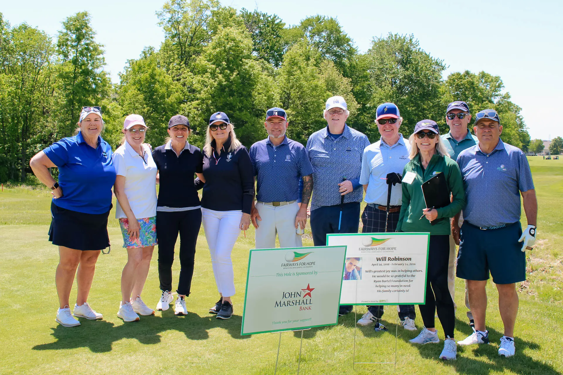 Golfers gathered around a sponsored hole sign at the Fairways for Hope tournament