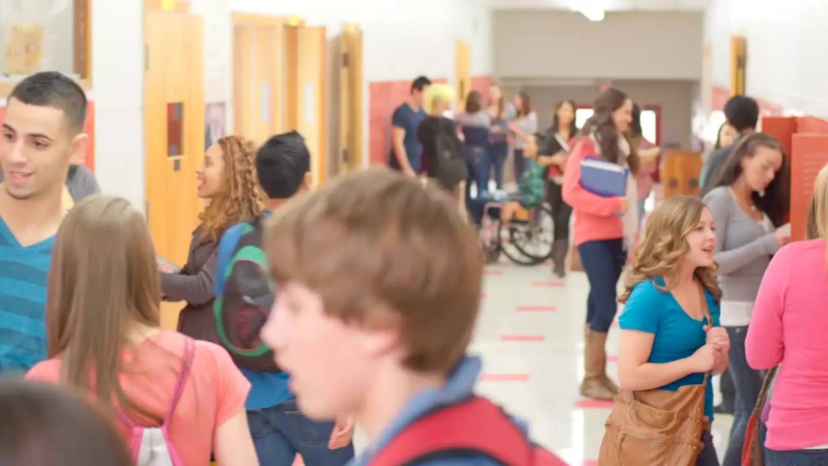 A crowded high school hallway with many teens engaged in conversation