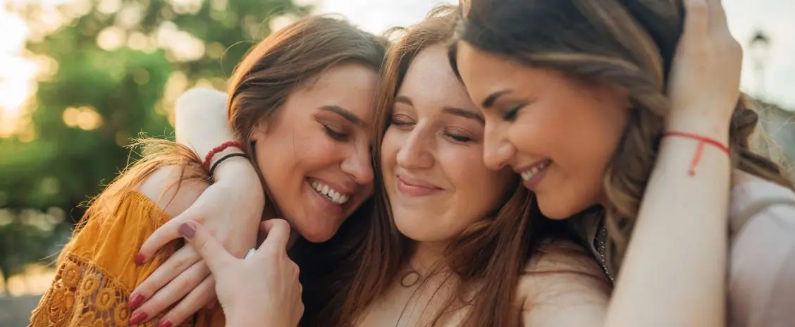 teen girl and a mother give a supportive hug to a third teen girl