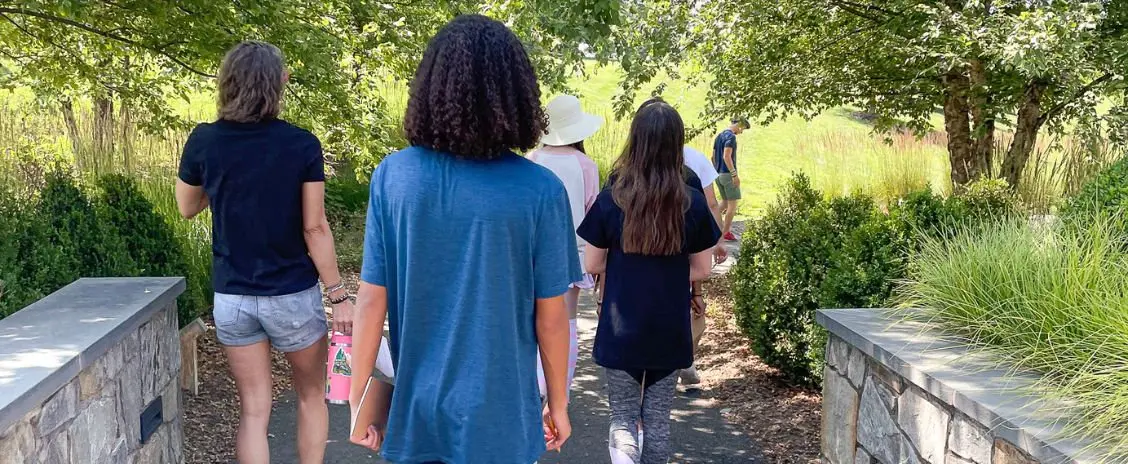 Group of teens walking away from viewer toward a garden path